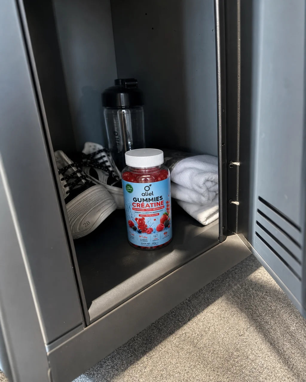 Casual smartphone photograph of the aliel GUMMIES CRÉATINE bottle placed inside a metal sports locke