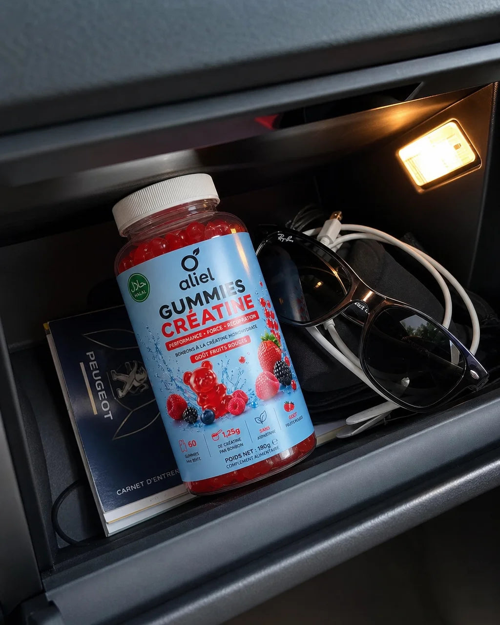 Smartphone photo inside a car glove compartment, the aliel GUMMIES CRÉATINE bottle lying among a car